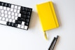 A cheerful workspace with black, yellow, and white stationery items spread out.