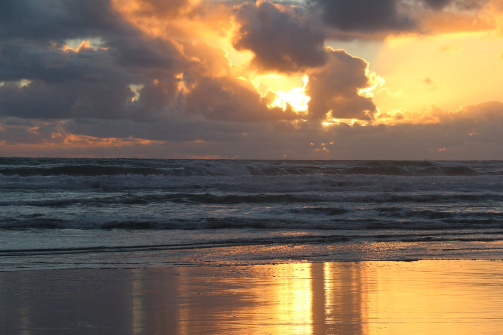o sol está se pondo sobre o oceano na praia