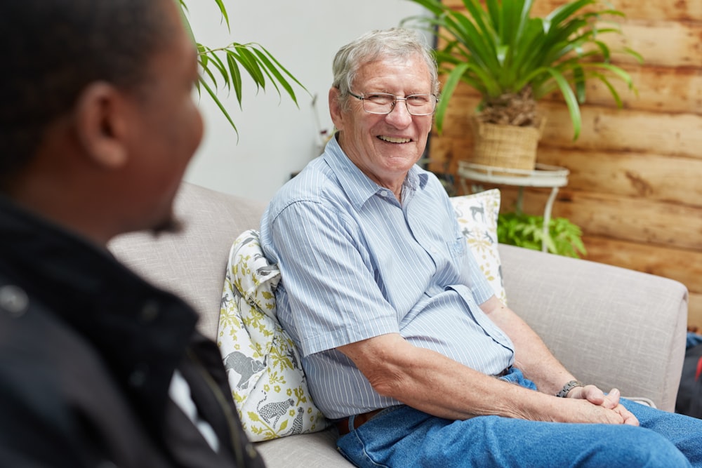 a man sitting on a couch talking to another man