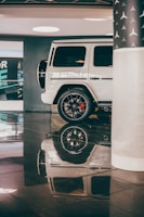 A shiny white SUV with polished rims displayed on a clean showroom floor.