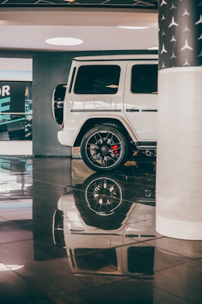A shiny white SUV with polished rims displayed on a clean showroom floor.