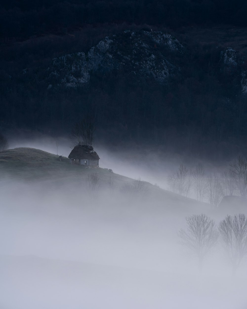 a foggy landscape with a house on a hill