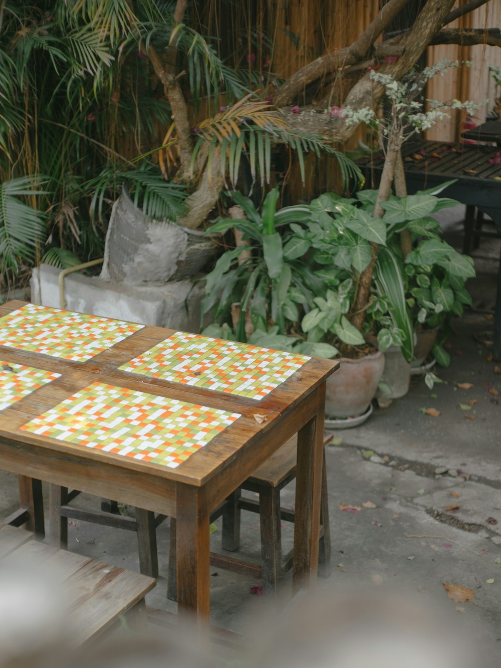 a wooden table with a tiled top in a garden