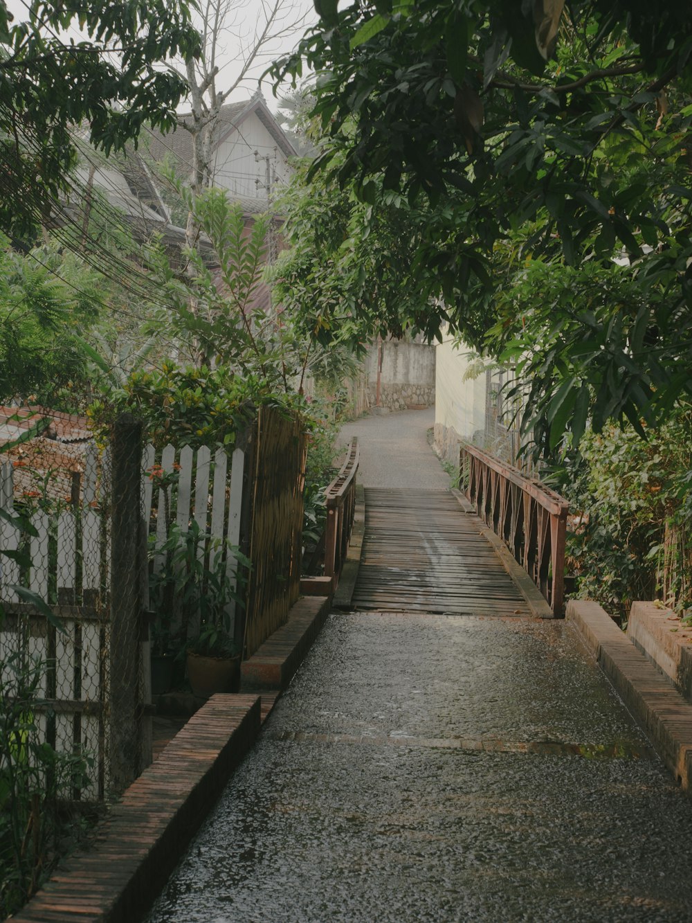 a walkway with a fence and a gate leading to a house