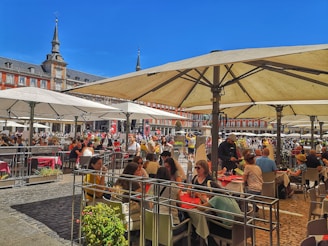 A lively city square in Spain bustling with people enjoying a sunny afternoon.