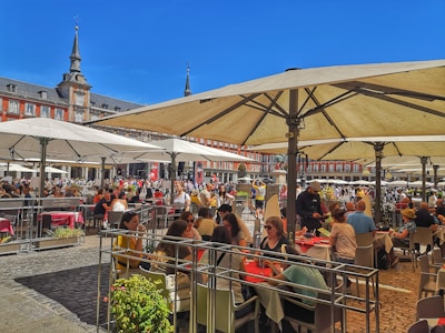 A bustling mixed-use plaza with people enjoying outdoor cafes and green spaces.