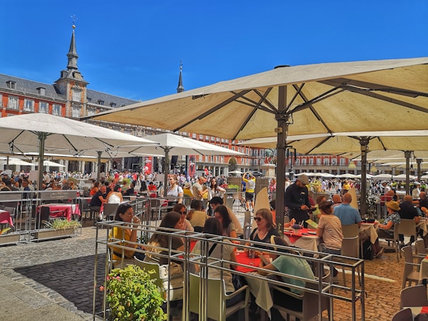 A lively city square in Spain bustling with people enjoying a sunny afternoon.