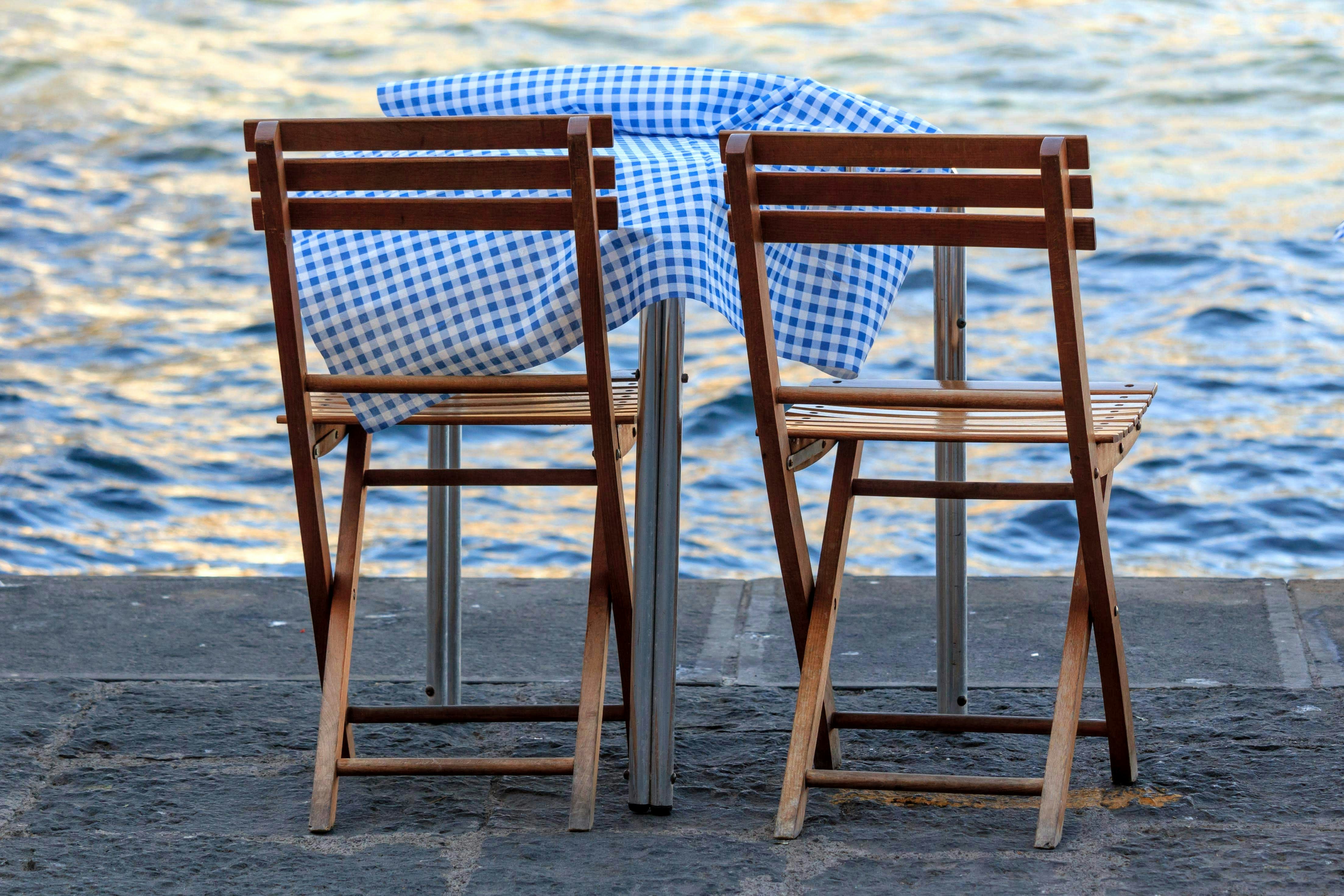 Two wooden chairs sitting next to each other near a body of water photo ...