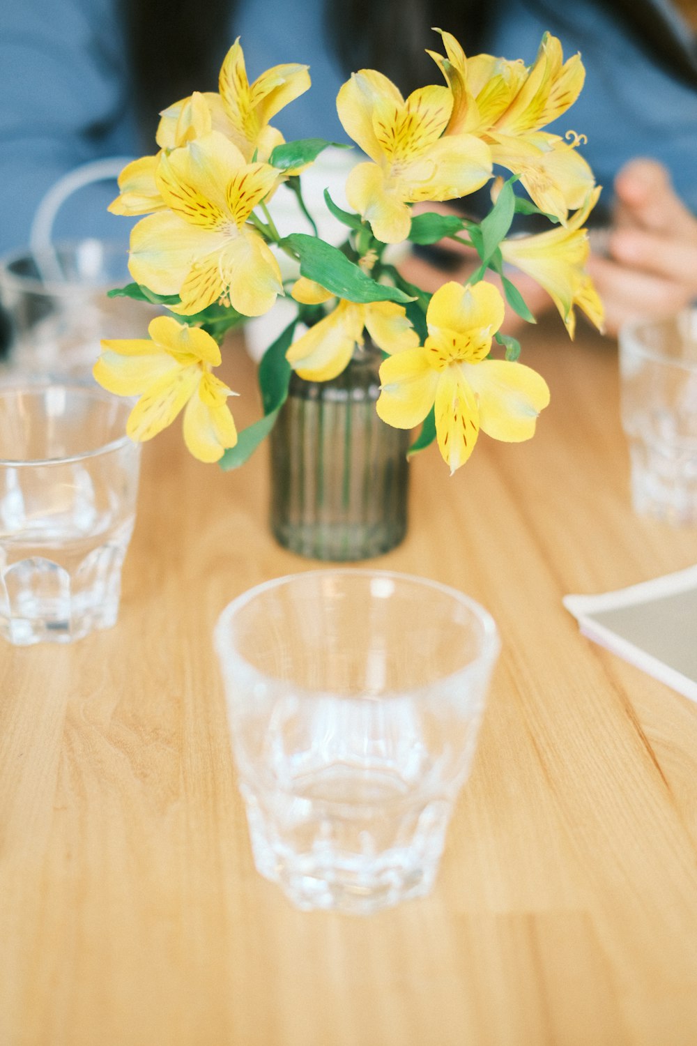 a vase with yellow flowers on a wooden table