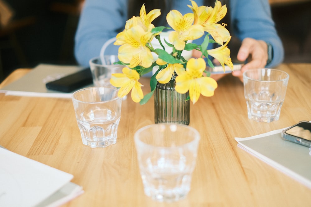 une personne assise à une table avec un vase de fleurs
