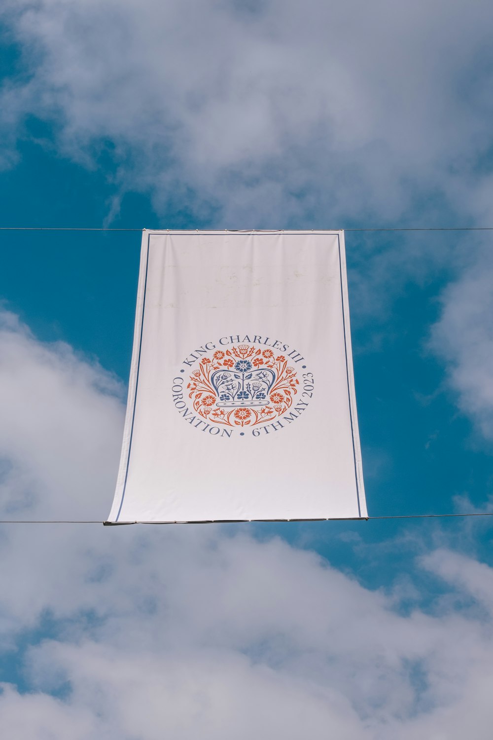 a white banner hanging from a wire on a cloudy day