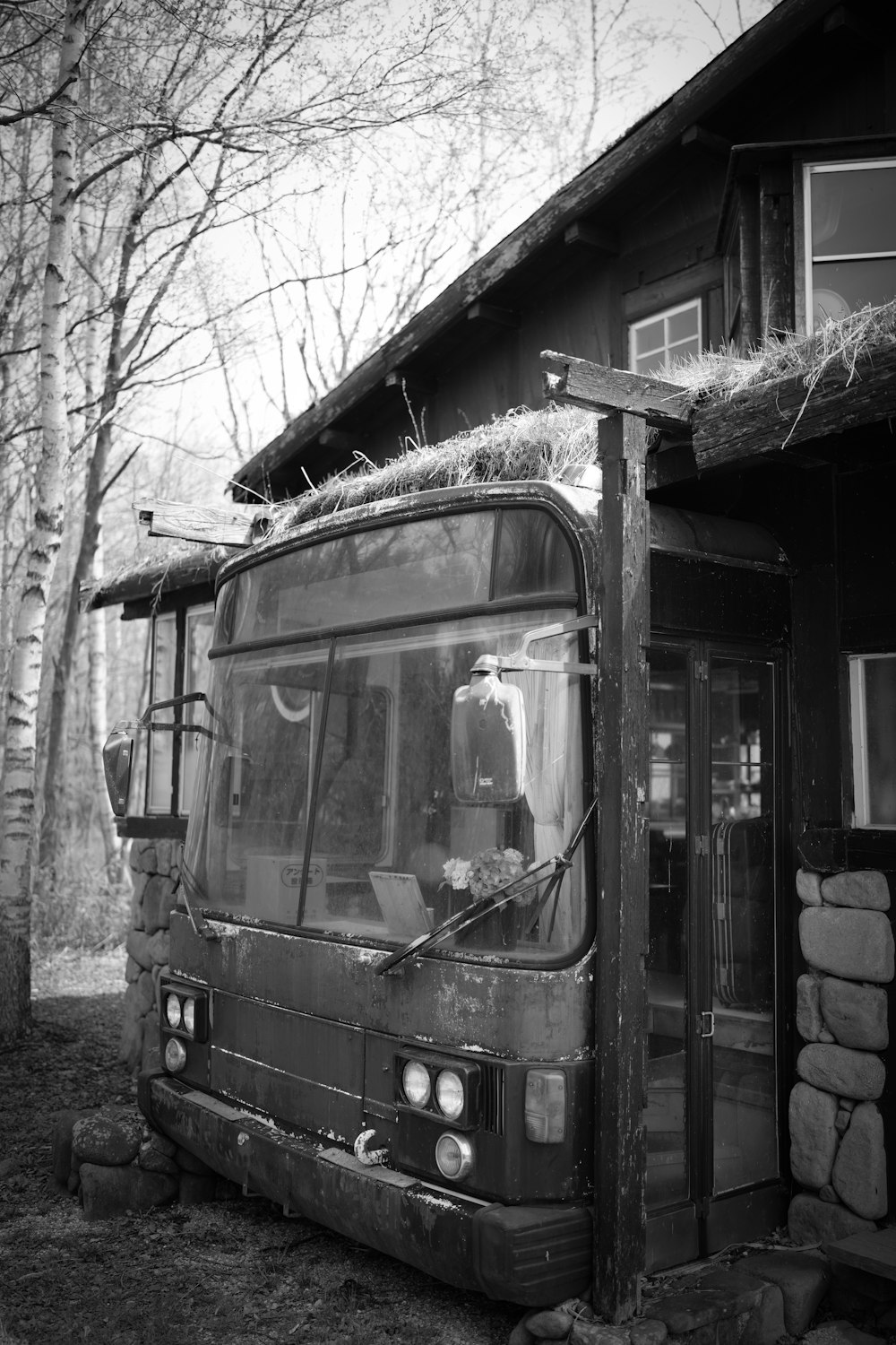 a black and white photo of a bus parked in front of a cabin