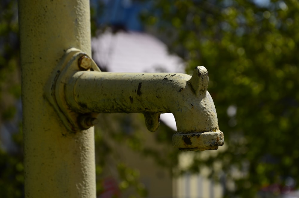a close up of a water faucet with trees in the background