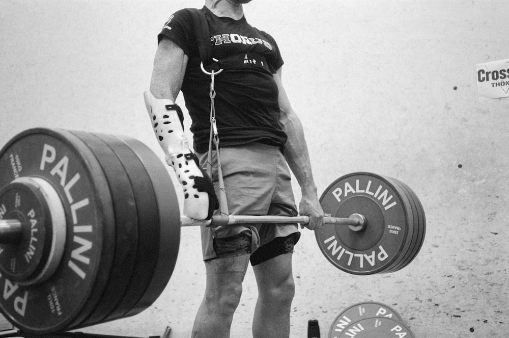 a man holding a barbell in front of a wall