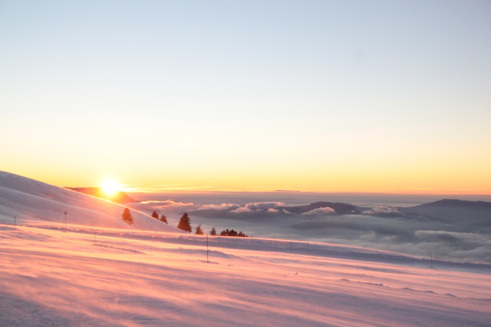 the sun is setting over a snowy mountain