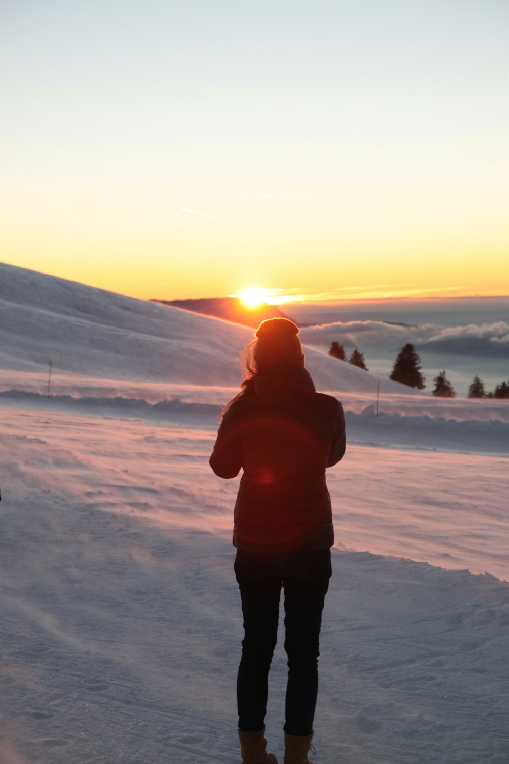 a person standing in the snow at sunset