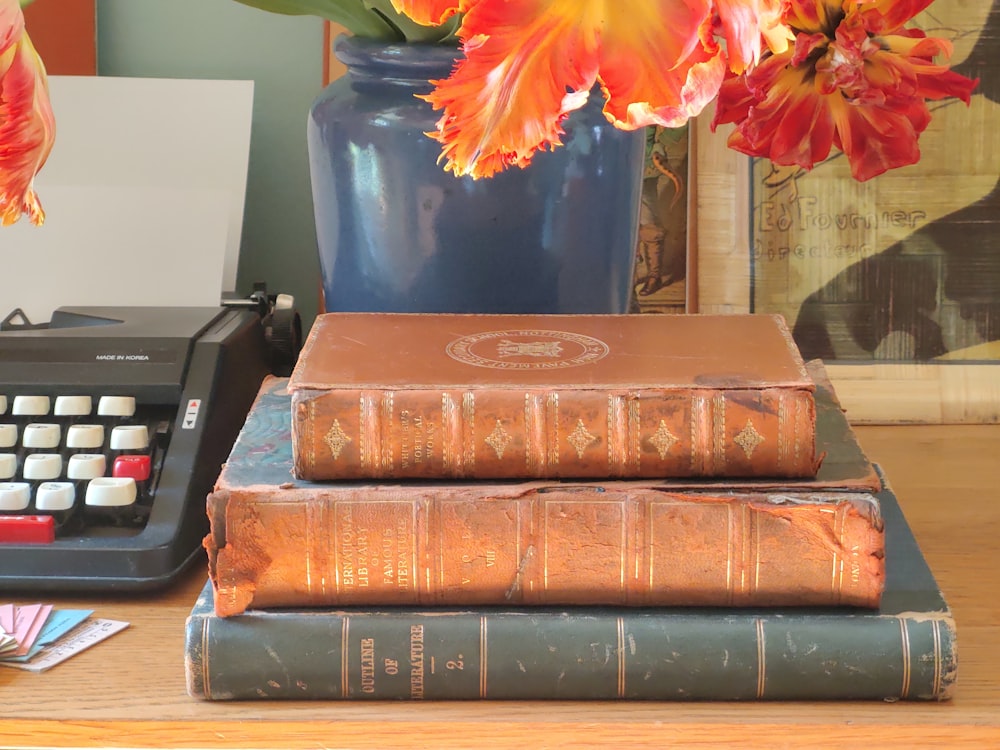 a stack of books sitting on top of a table next to a typewriter