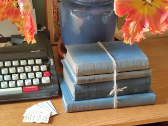 a stack of books sitting on top of a table next to a typewriter