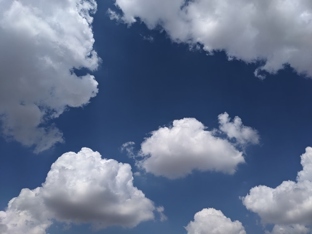 a blue sky with white clouds and a plane flying in the sky