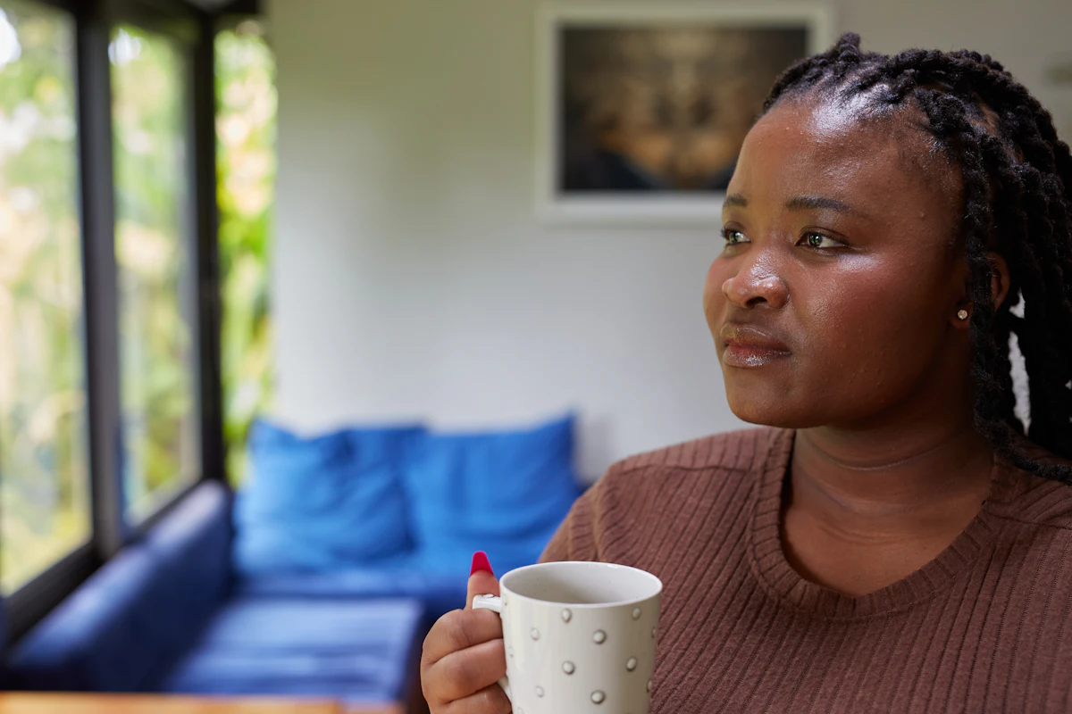 A woman holding a warm cup, looking out a window