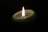 Forest green Wednesday candle glowing softly on a wooden table.