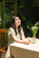 A smiling woman journaling with a backdrop of plants, embodying warmth and clarity.
