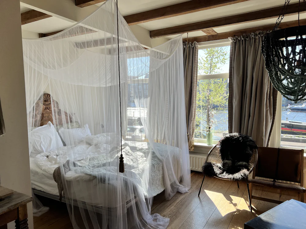 Twin room with a canopy bed and a reading chair