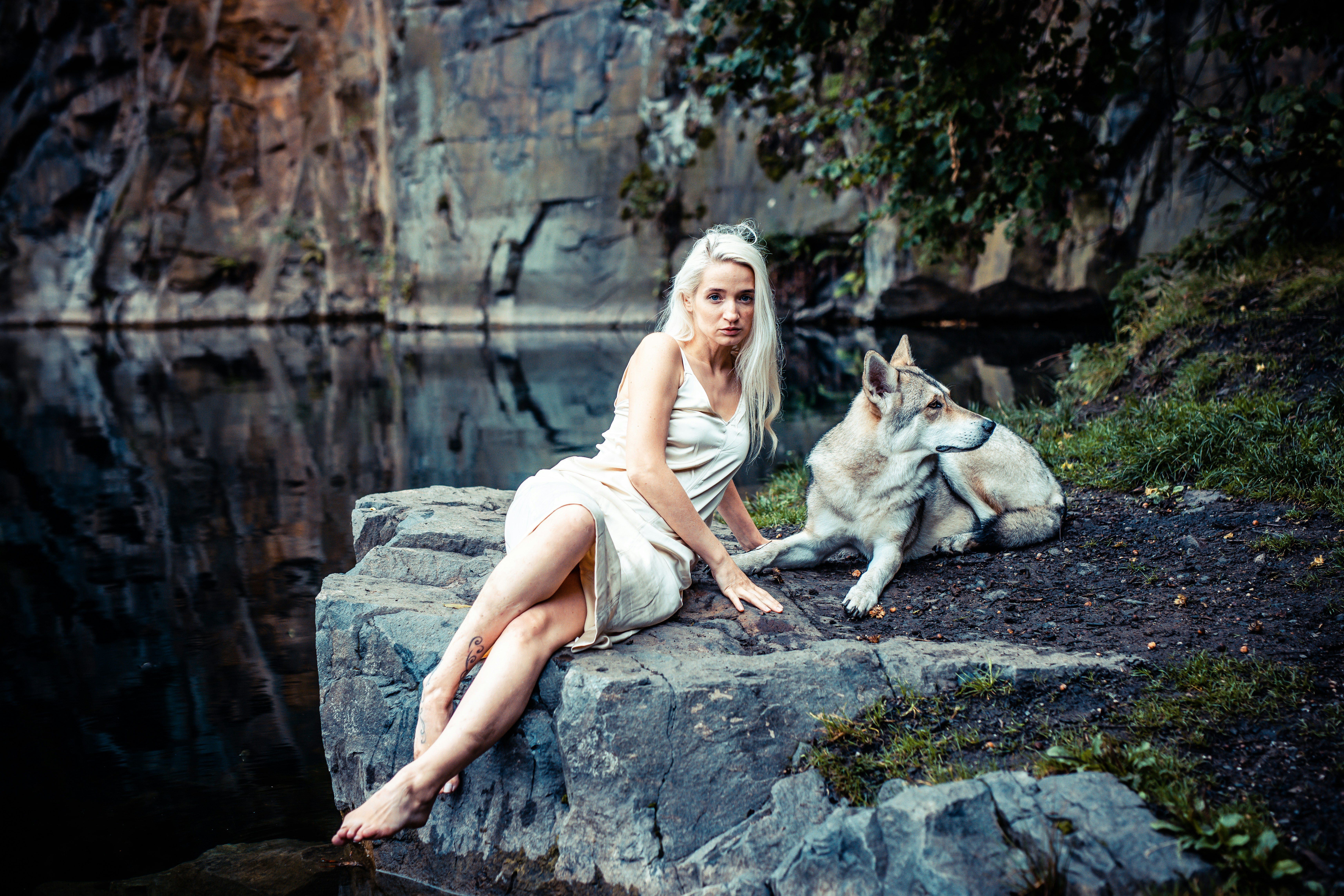 a woman sitting on top of a rock next to a dog