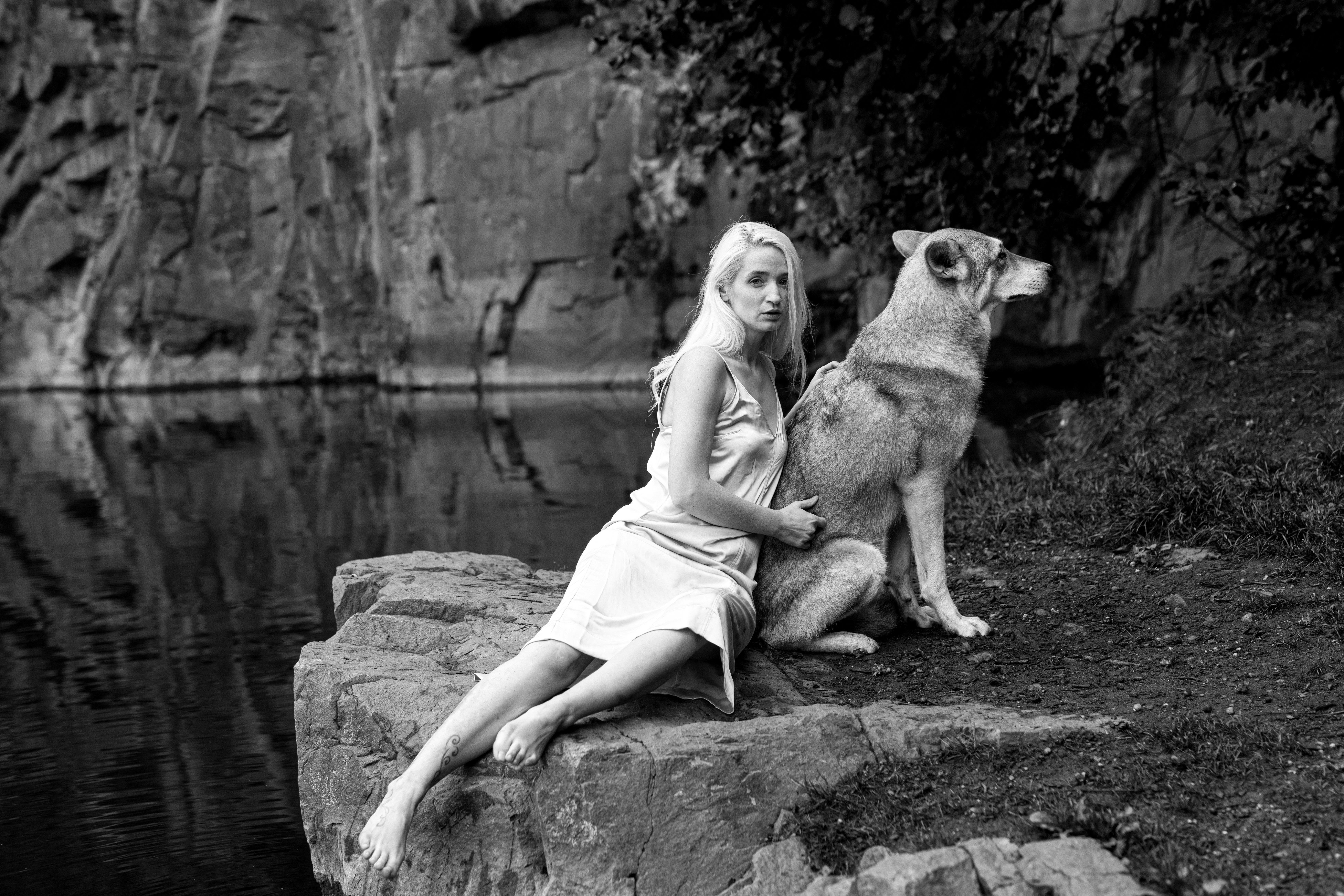 a woman sitting on a rock next to a dog
