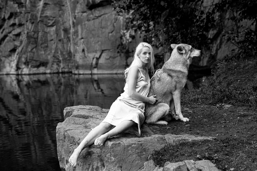 a woman sitting on a rock next to a dog