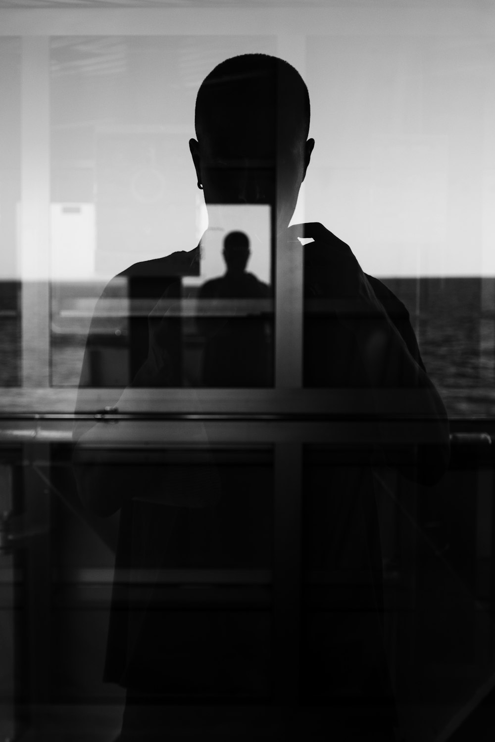 a man standing in front of a window next to the ocean