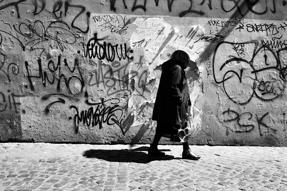 a person standing in front of a wall covered in graffiti