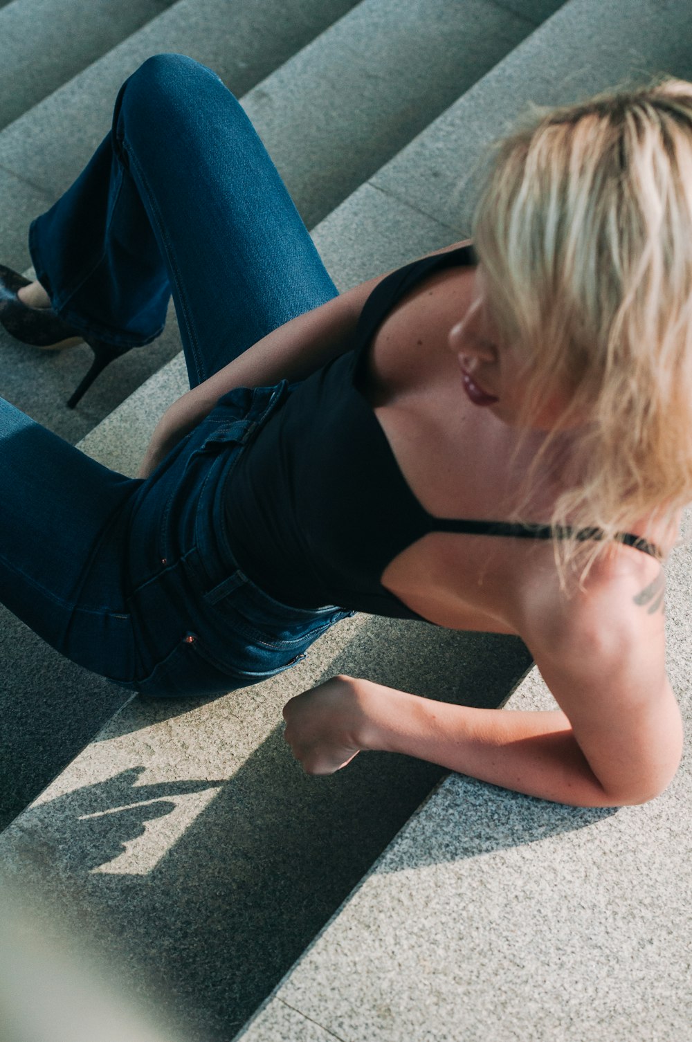 a woman in a black top is sitting on some steps