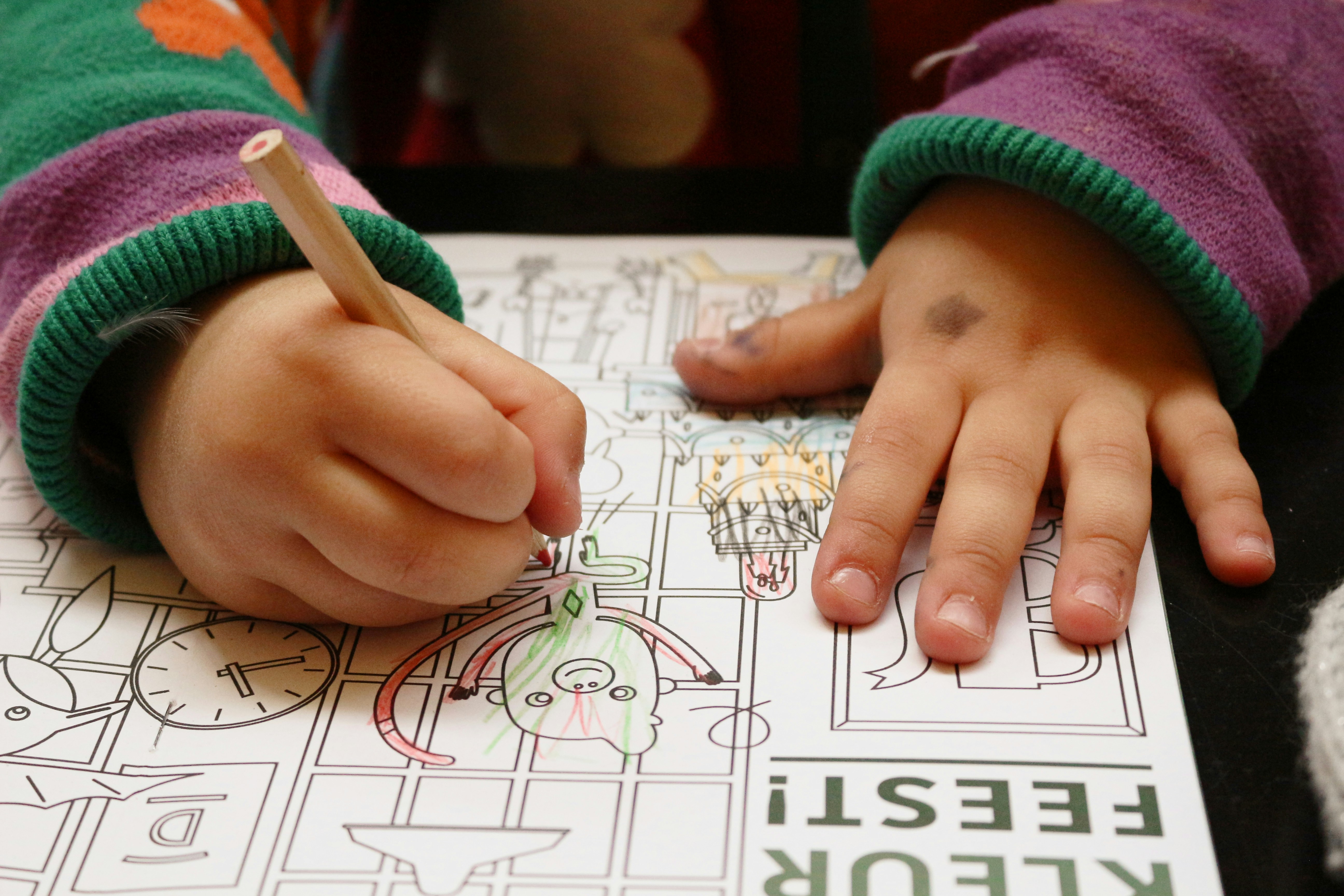 Children coloring Christmas tree worksheets at a school table