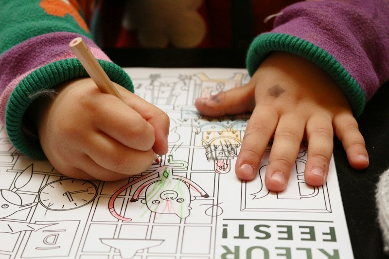 A child's hands drawing on paper at a table