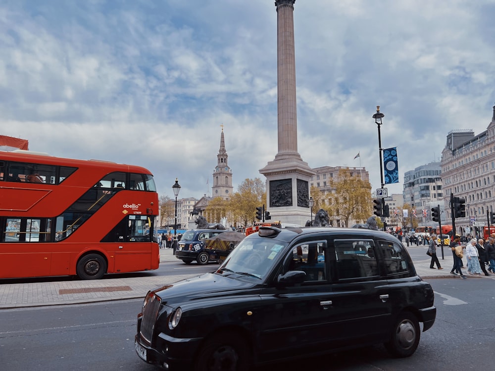 a black taxi cab driving down a street next to a red double decker bus