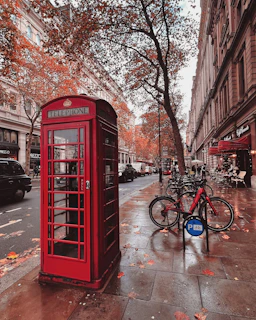 a red phone booth sitting on the side of a street