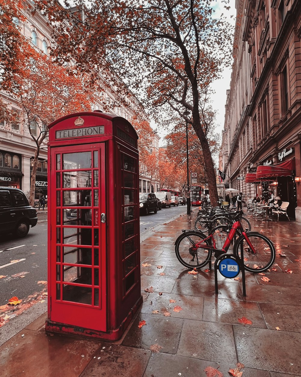 a red phone booth sitting on the side of a street