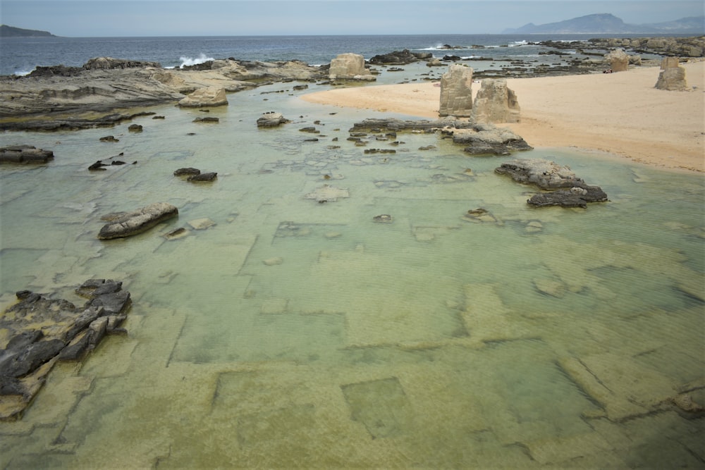 um corpo de água cercado por rochas e areia
