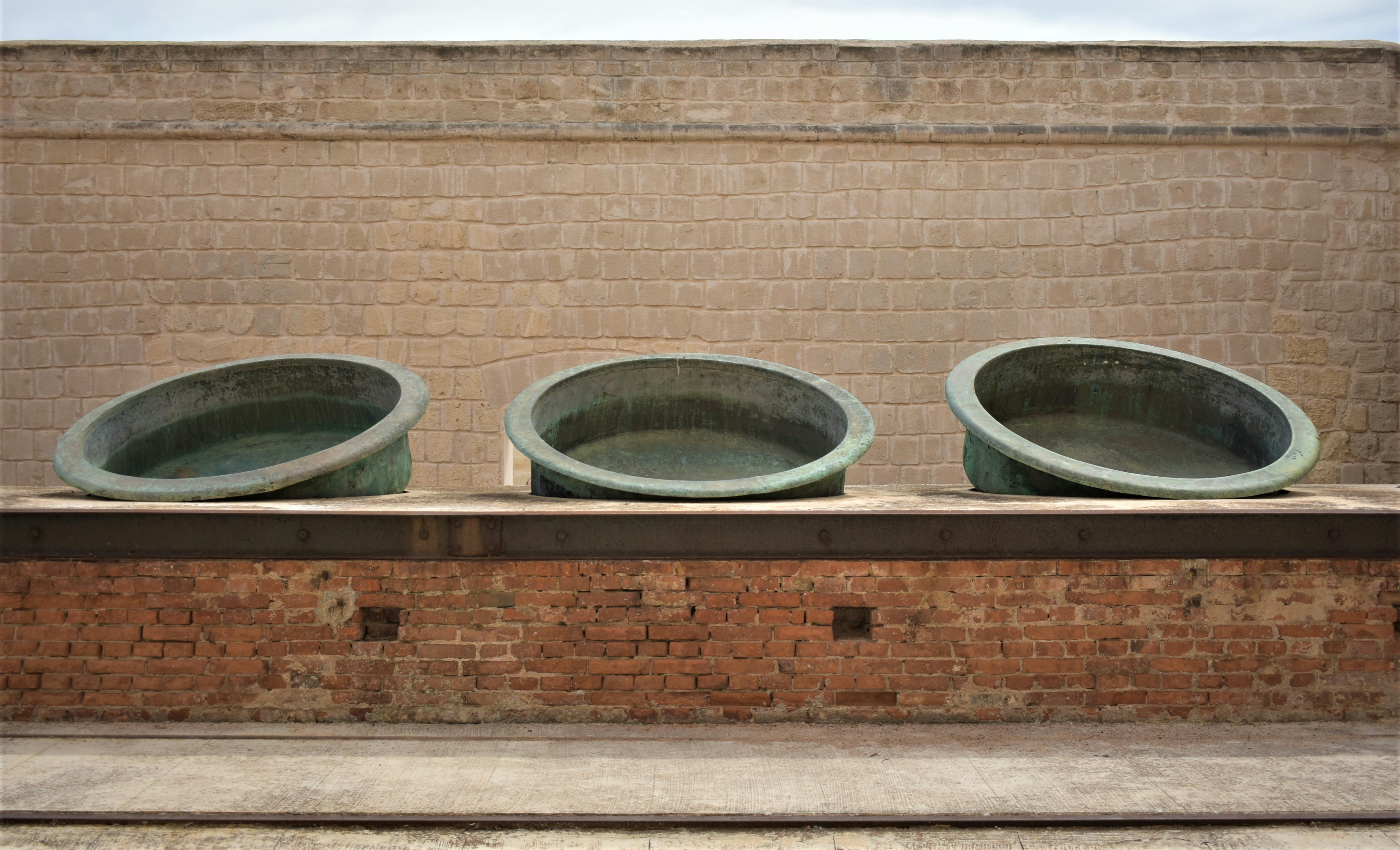 three stone bowls sitting on top of a brick wall