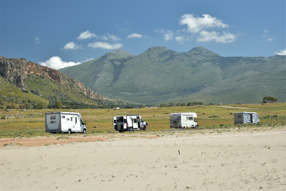 a group of four travel trailers parked in a field