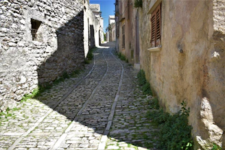 a narrow cobblestone street with a stone building in the background