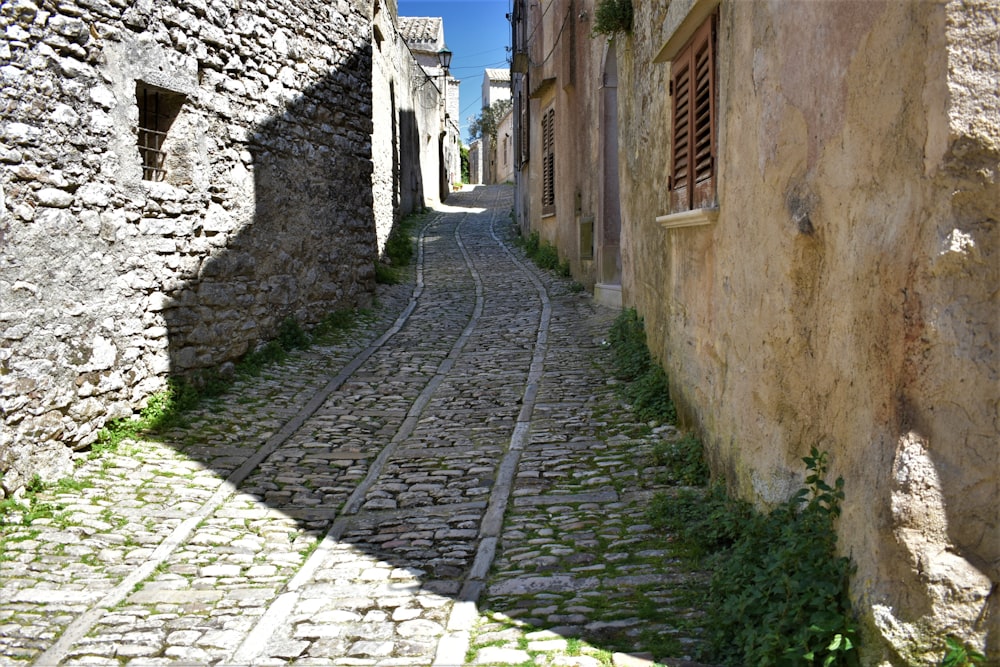 a narrow cobblestone street with a stone building in the background