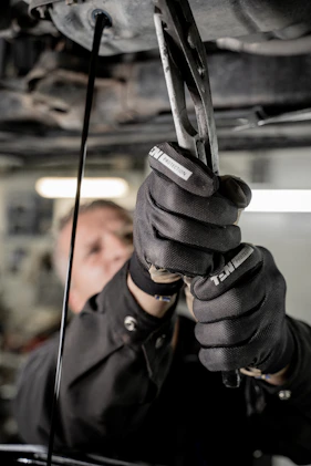 Technician in uniform fixing a clogged pipe with professional tools.