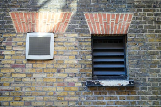 a brick wall with a window and a shutter
