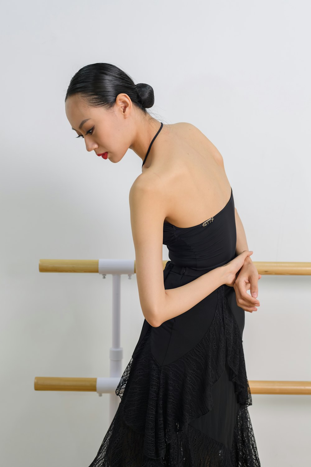 a woman in a black dress standing in front of a white wall