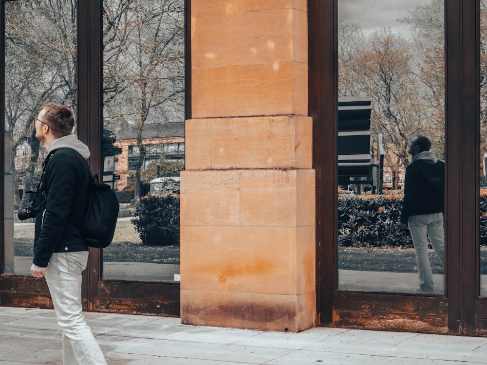 a woman walking down a sidewalk past a tall building