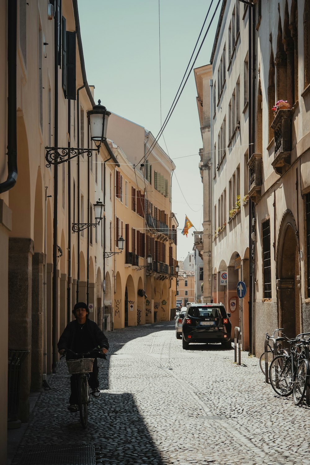 a man riding a bike down a cobblestone street