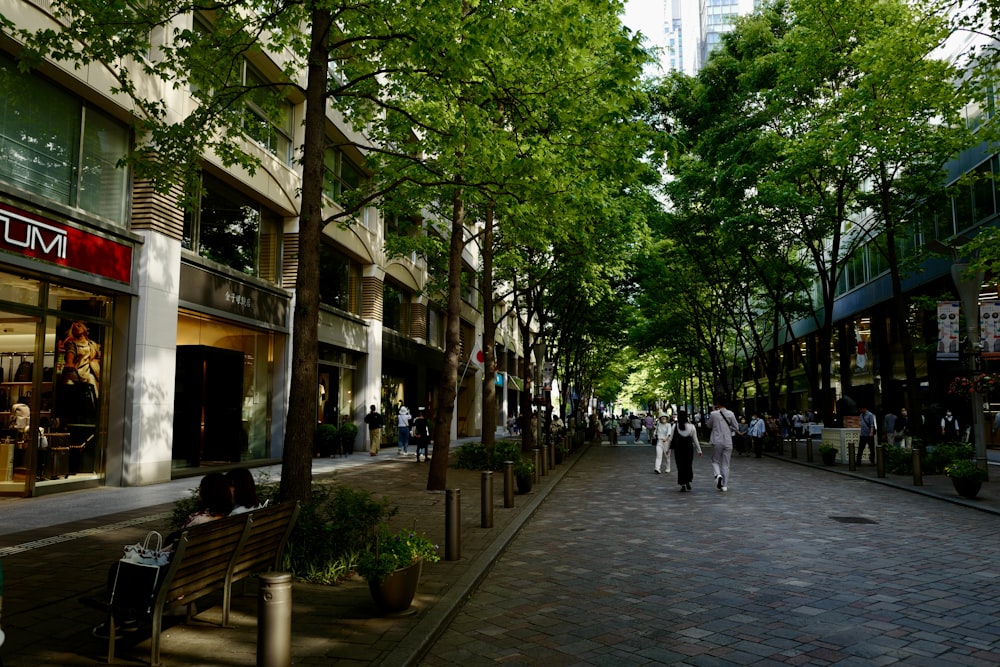 a group of people walking down a street next to tall buildings