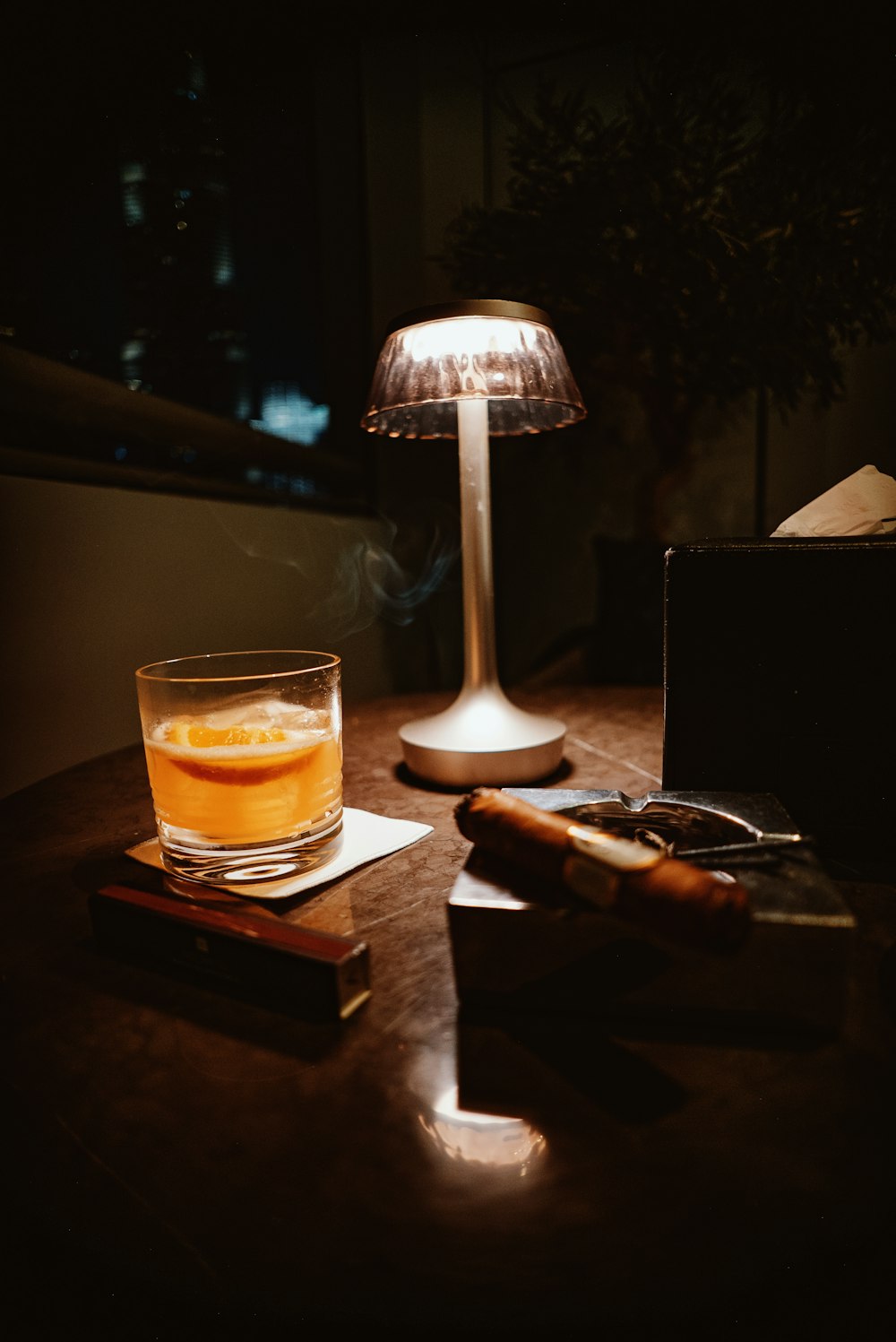 a glass of alcohol sitting on top of a wooden table
